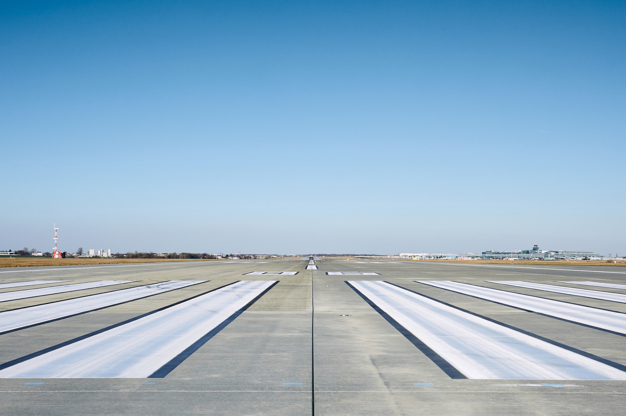 Surface level of airport runway with road marking against clear sky.